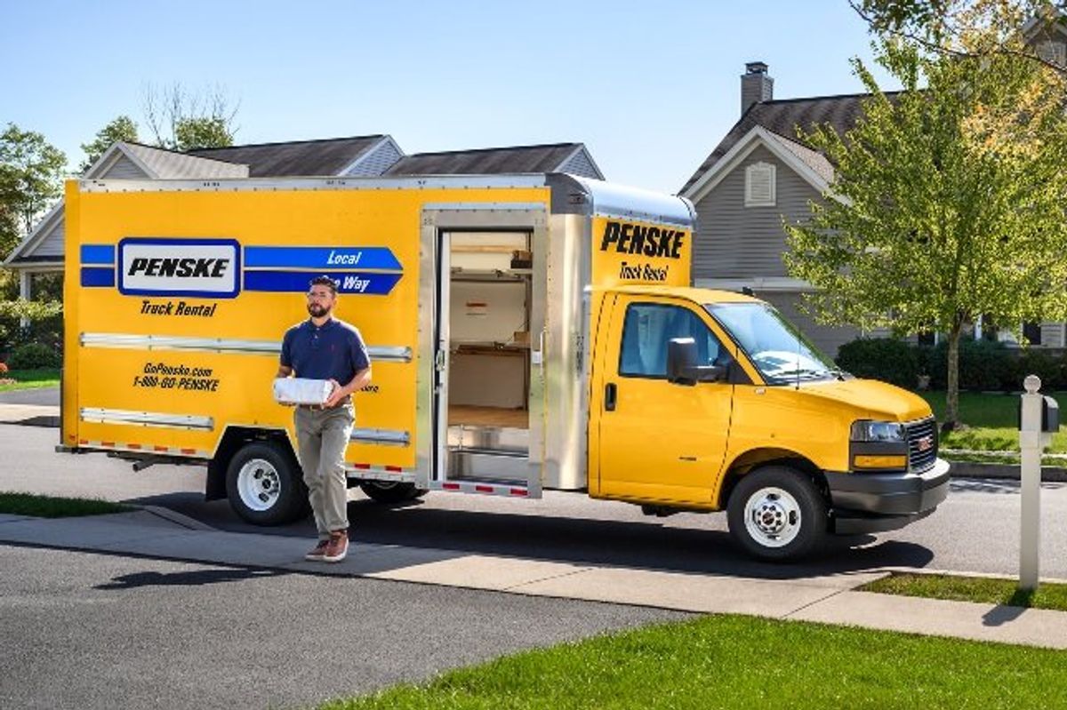 A yellow Penske box truck with shelves and curbside door.